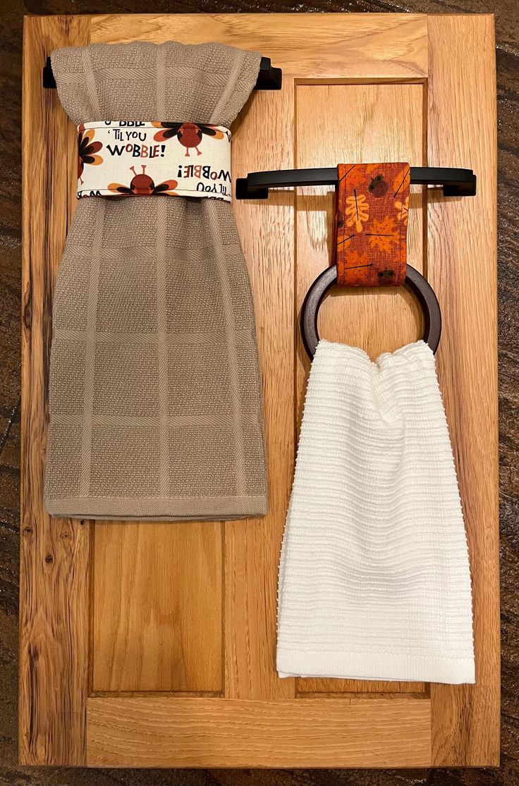 two towels and a towel holder on a wooden door with an ironing board in the background