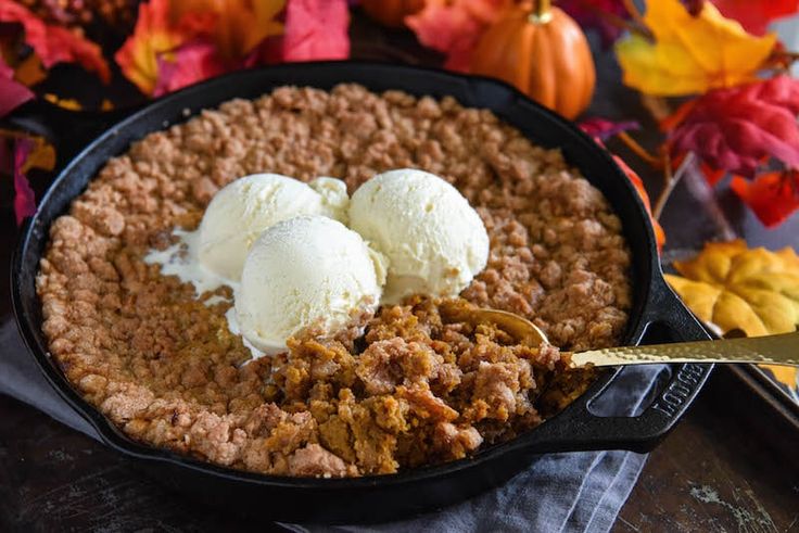 two scoops of ice cream on top of a pie in a black skillet