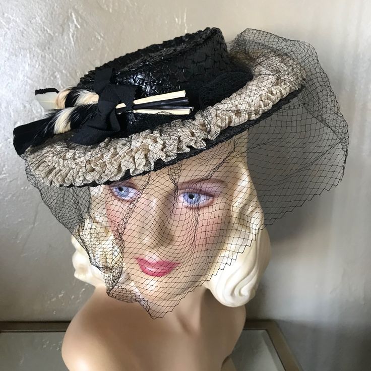 This Is An Outstanding 1930s' Black Straw Tilt Medium Brim Hat With Creme Fabric Netting Attached Over The Brim. The Delicate Fabric Trim Is Creatively Folded. The Flat Crown Is Surrounded By A Black Grosgrain Band Ending In A Bow At The Front. The Bow Holds A Pair Of Intricate And Matching Black And Creme Colored Feather Trimming.There Are Two Black Grosgrain Straps At The Back, Held Together By A Circle Of Elastic, To Hold The Hat In A Tilted Position. A Black Veil Completes The Look. The Veil Can Cover The Face, As Was The Fashion Of The Era, Or Placed On Top Of The Brim. Tilt Hats Were Popular In The 1930s And 1940s. They Were Worn At An Angle And Held To The Back Of The Head By A Stra Fitted Retro Cream Hat, Retro Fitted Cream Hat, Retro Cream Hat, Vintage Beige Mini Hat For Party, Beige Vintage Mini Hat For Party, Vintage Black Hat For Spring, Vintage Cream Hat For Evening, Fitted Brimmed Top Hat For Vintage Events, Vintage Beige Top Hat With Curved Brim