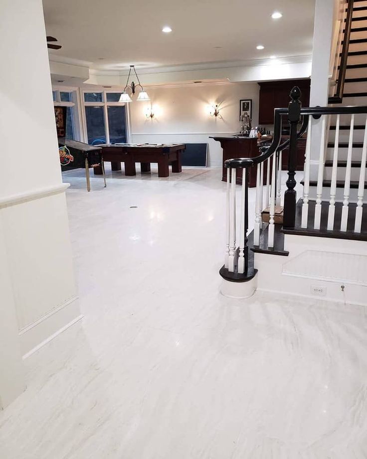 an empty living room with white marble flooring and black bannister railings