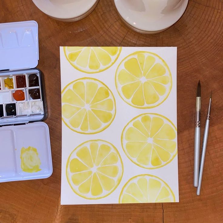 there are some lemons that have been cut in half and watercolor paints on the table