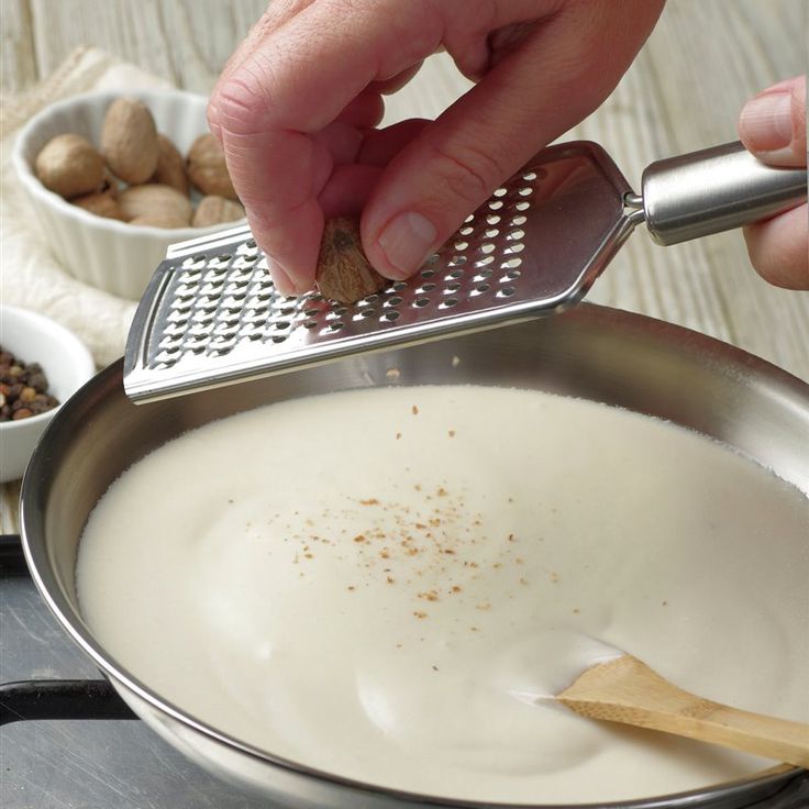 a person grating nuts in a pan with a grater on the stove top