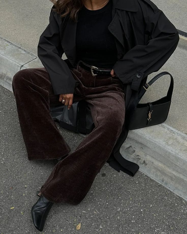 Embrace the chill with a pair of corduroy pants, perfect for chic fall and winter outfits. We just love this dark academia look with dark brown corduroy pants, a black trench coat and a YSL hobo bag – you can't go wrong with this color combo. Brown Velvet Trousers Outfit, Moody Winter Outfits, Classic Oversized Outfits, Chocolate Brown Corduroy Pants Outfit, Chocolate Brown Trousers Outfit Women, Curdoroy Pants Outfit Womens Brown, Dark Green Boots Outfit, Black Courdory Pants Outfit, Brown Pants Winter Outfit