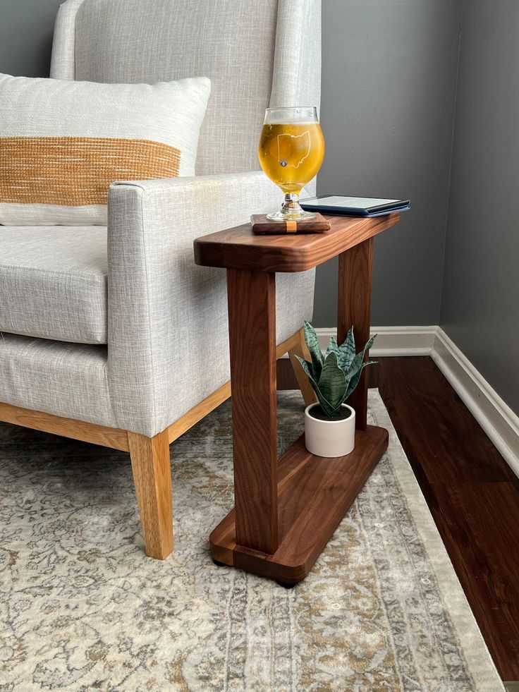 a glass of beer sitting on top of a wooden table next to a white chair