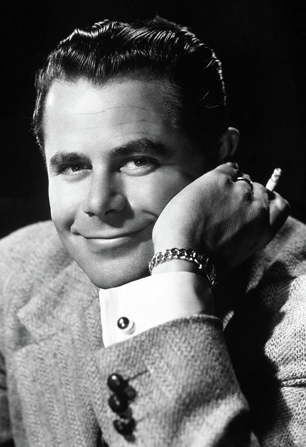 a black and white photo of a man in a suit with his hand on his chin