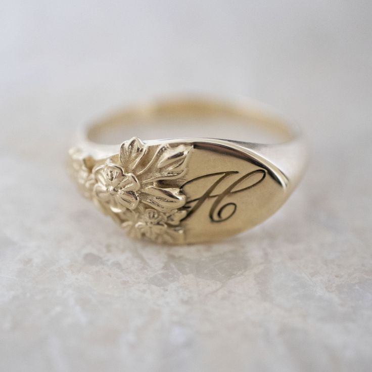 This vintage-inspired floral ring is a row of dainty flowers wrapped around your fingers. Handmade and polished, it is available in solid 8K and 14K gold. This item is engravable with text or monogram of your choice at no extra cost. The initals are engraved onto the ring and embedded in the 3D model for a flawless embossed finish. It is also possible to add a diamond or birthstone or diamond to this ring at an additional fee. Please inquire for details. A few notes about our gold: - Though we d Classic Round Birth Flower Jewelry, Heirloom Yellow Gold Jewelry With Birth Flower, Heirloom Yellow Gold Birth Flower Jewelry, Heirloom Birth Flower Jewelry, Elegant Gold Signet Ring With Birth Flower, Heirloom Birth Flower Jewelry For Anniversary, Heirloom Wedding Flower Ring With Engraving, Classic Flower Shaped Jewelry For Wedding, Classic Flower-shaped Jewelry For Wedding