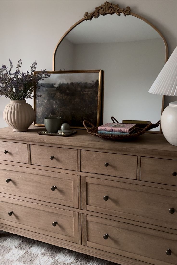 a dresser with a mirror and vase on top