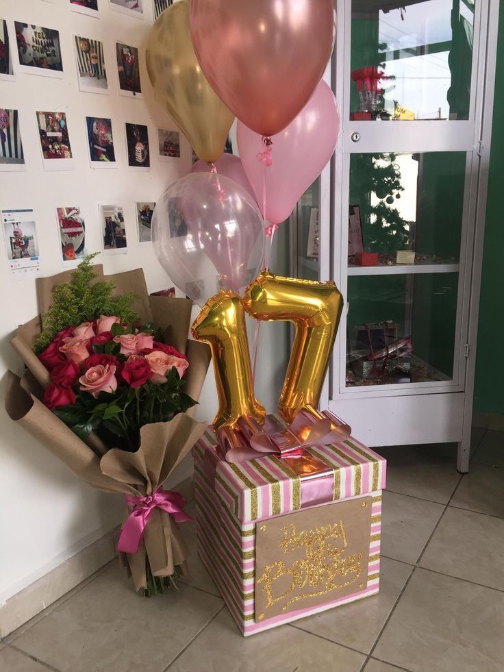 a bunch of balloons that are sitting on top of a box with some flowers in it