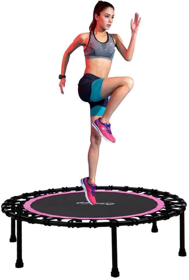 a woman jumping on a trampoline with her hands in the air and one leg up