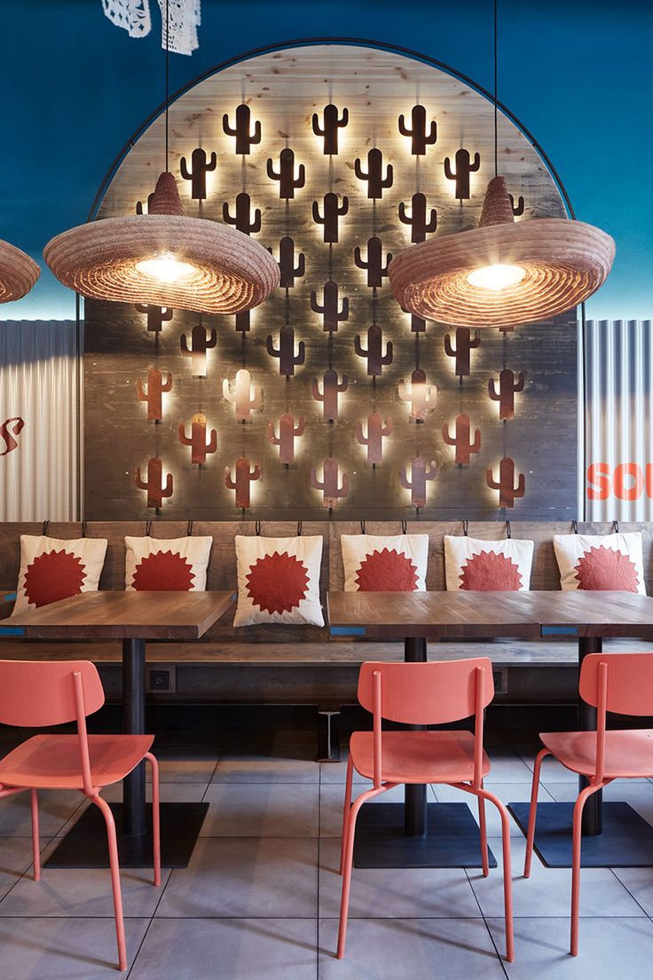 the interior of a restaurant with red chairs and cactus decorations on the wall behind them