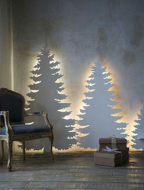 a living room with christmas trees on the wall and presents in front of it next to a chair