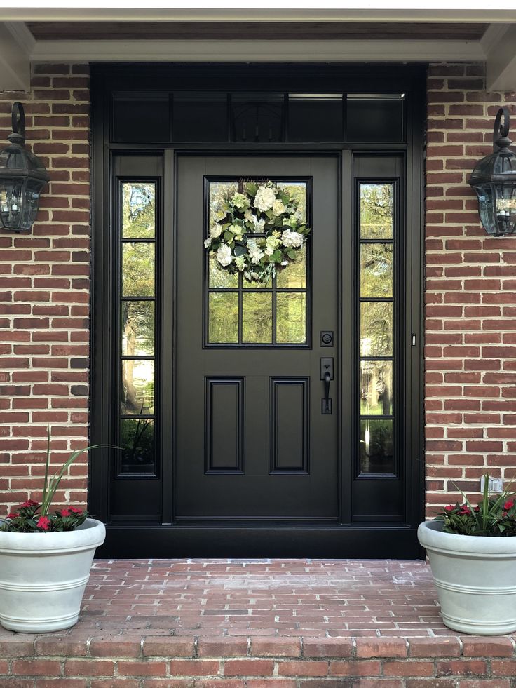 a black front door with two planters on either side