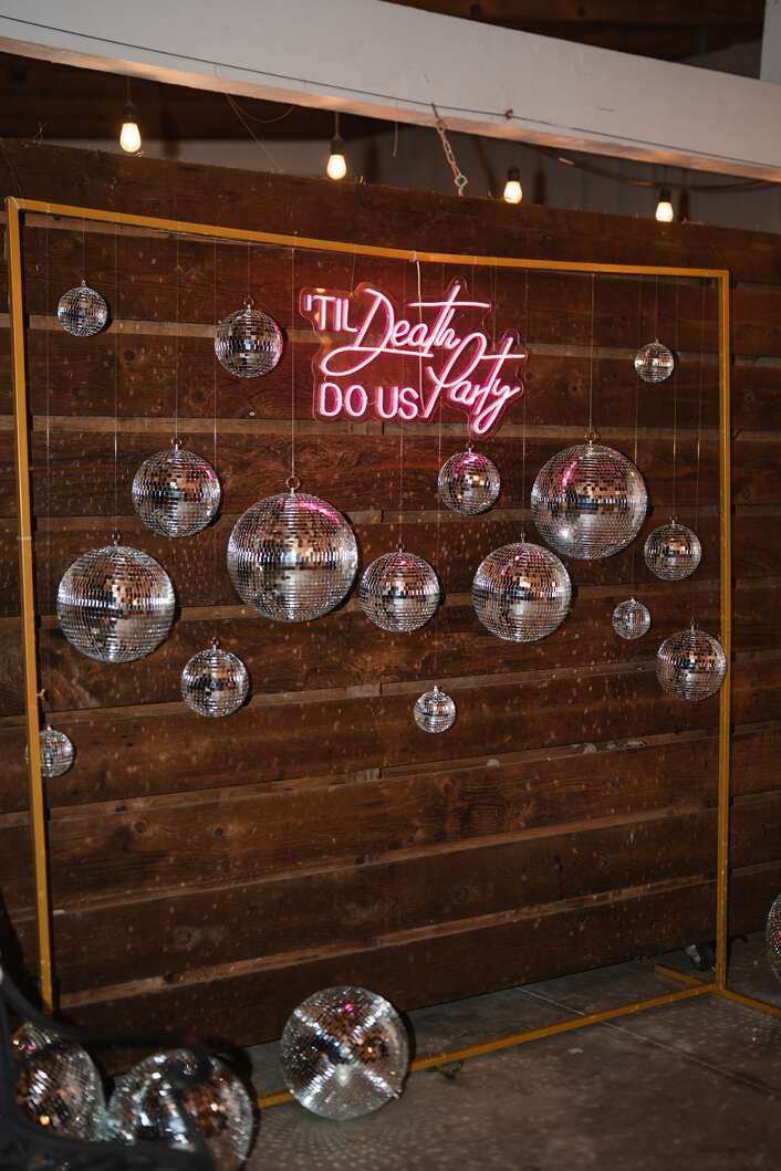 a wooden wall with disco balls hanging from it's sides and a neon sign that reads the dead city do us pay