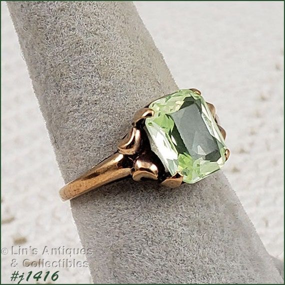 I purchased this vintage ring over 30 years ago at a local antique store that has long since closed. I fell in love with the vintage mounting and the beautiful light green color stone. Unlike most of my rings that I have listed, I actually wore this ring on a somewhat regular basis.  The green stone was listed as peridot. It measures 3/8" x 5/16" and is emerald cut. The band measures 1/16" at bottom and is marked 10k. The ring is size 7 (sorry, when I listed this ring, I listed the size in the i Antique 14k Stamped Emerald Ring, Collectible Green 14k Stamped Jewelry, Green Birthstone Rings For Formal Occasions, Formal Emerald Cut Green Topaz Ring, Antique Green Ring With 17 Jewels, Antique Green Jewelry Stamped 14k, Antique Green 14k Stamped Jewelry, Antique Hallmarked Emerald Ring, Classic Green Topaz Ring Gift