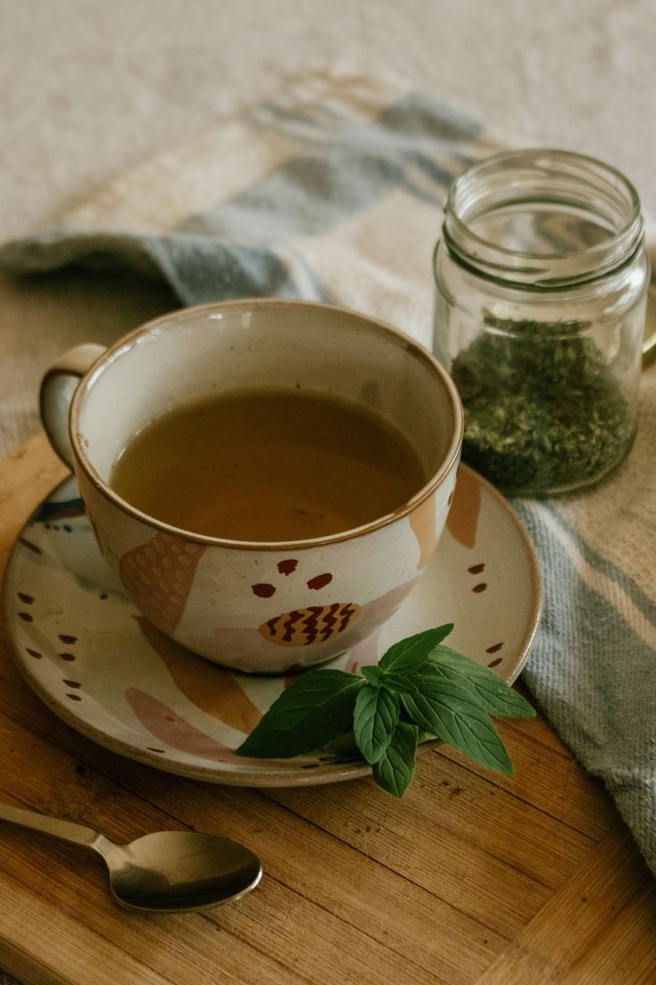 a cup of tea sits on a saucer next to a spoon