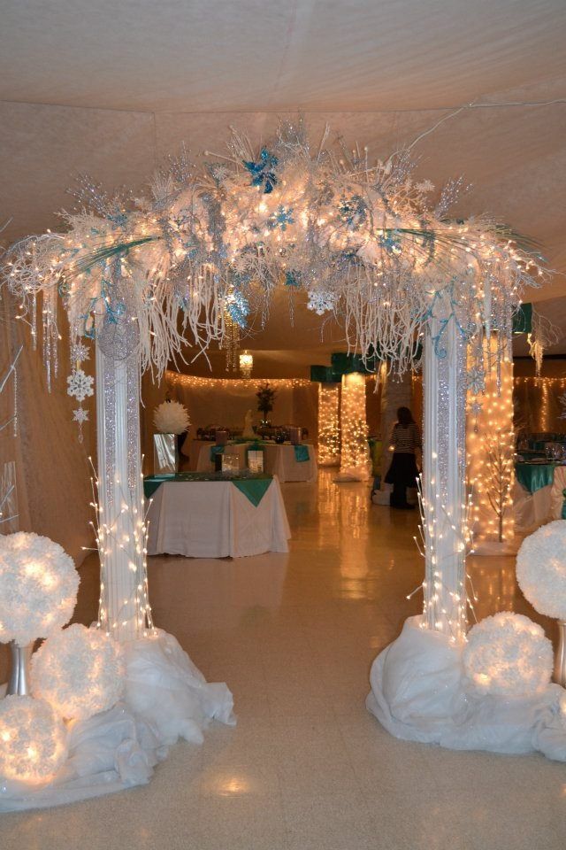 a white wedding arch decorated with snowflakes and fairy lights for the entrance to the reception hall