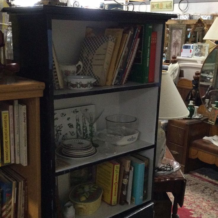 a bookshelf filled with lots of books in a living room next to a lamp