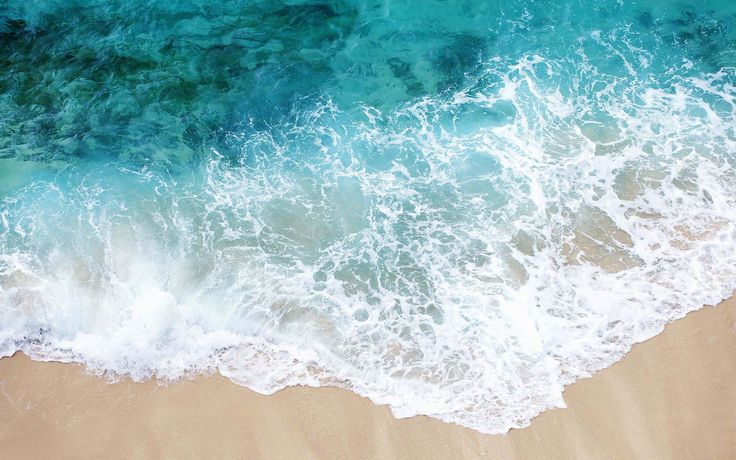 an aerial view of the ocean waves and sand