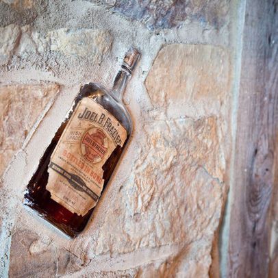 a bottle of whiskey sitting on top of a stone wall