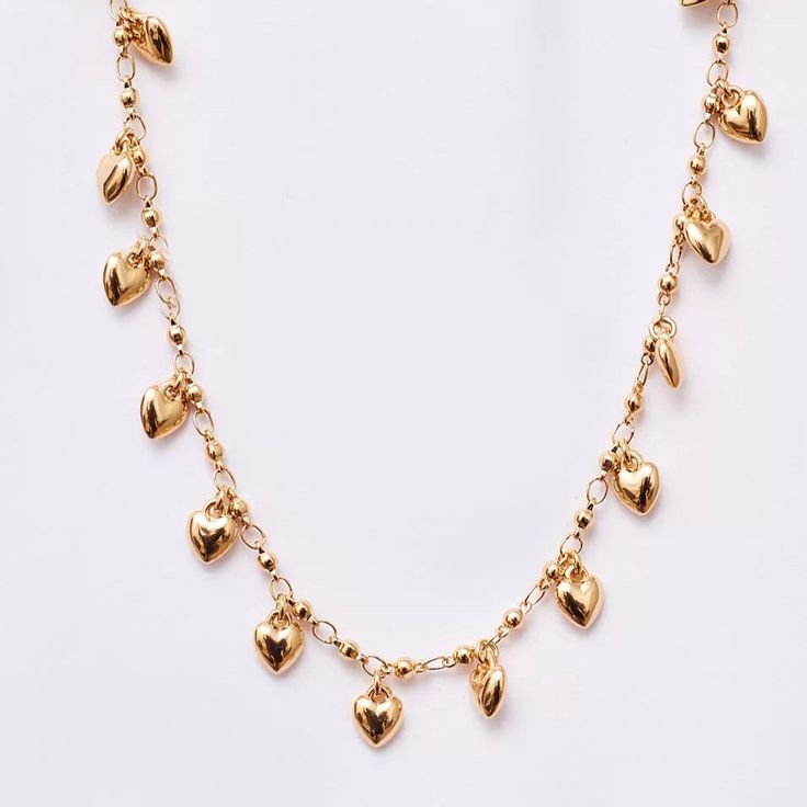 The Little Hearts Choker is made of brass with a beautiful gold plating. This piece, featuring a delicate chain with heart-shaped pendants, is a versatile and exceptionally elegant choice. With a length of 32 cm and a 7 cm extender, this choker adjusts perfectly to your style. Gold Metal Heart Choker Necklace, Gold Choker Necklace For Valentine's Day, Adjustable Gold Heart Chain Necklace, Adjustable Gold Heart Choker Necklace, Adjustable Gold Plated Necklaces With Heart Charm, Adjustable Gold Heart Necklace With Clavicle Chain, Adjustable Gold Heart Charm Necklace, Adjustable Gold Charm Necklaces With Heart Charm, Gold Heart Charm Choker Necklace