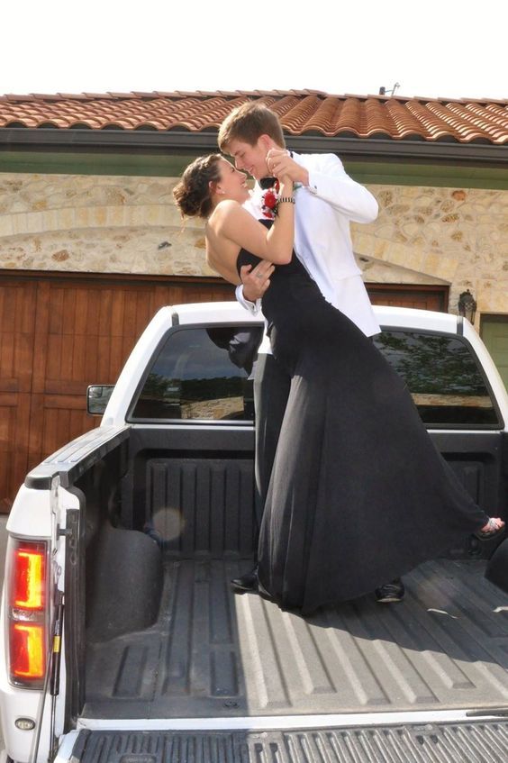 a man and woman standing in the back of a pickup truck with their arms around each other