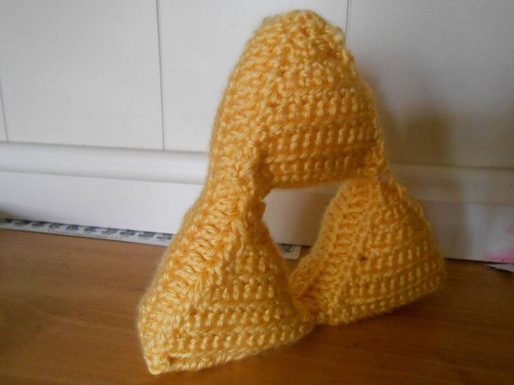 a crocheted yellow hat sitting on top of a wooden floor next to a white door