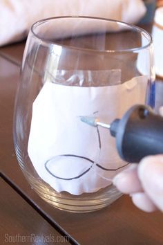 a person is drawing on a glass with a pen and inking it into paper