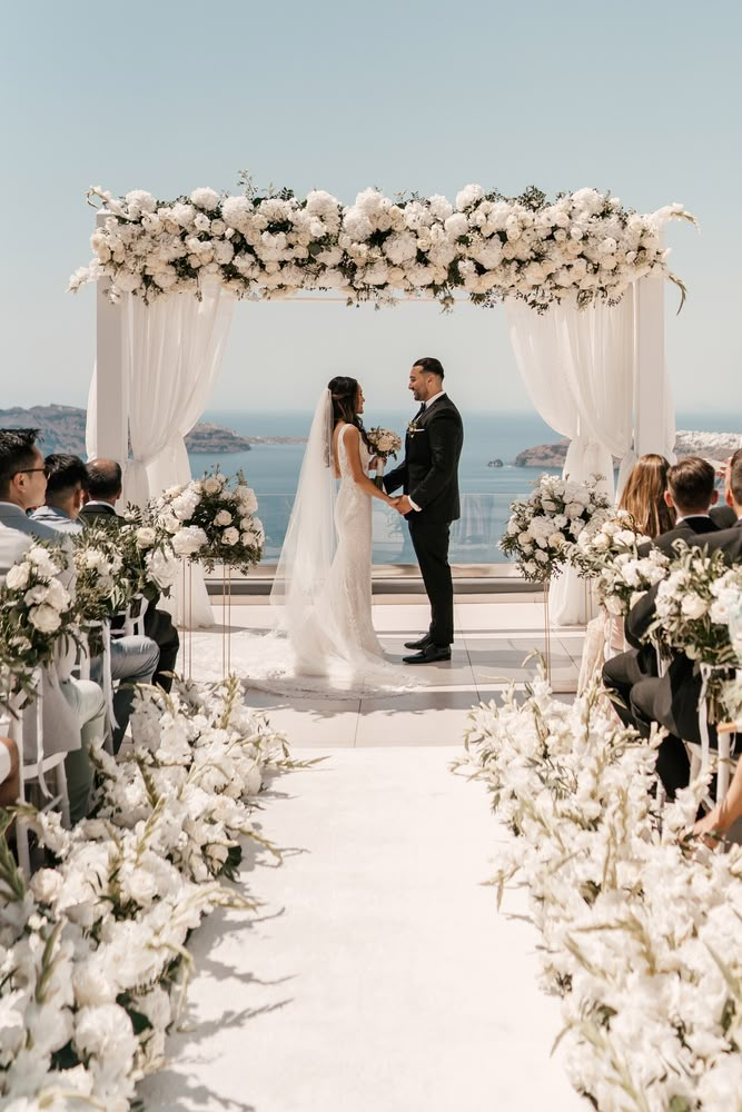 a bride and groom standing at the end of their wedding ceremony in front of an ocean view