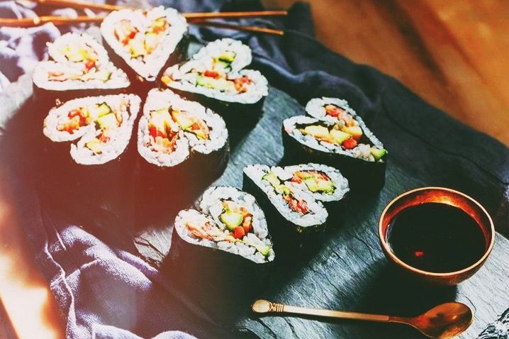 sushi and chopsticks on a black cloth with a small bowl of dipping sauce