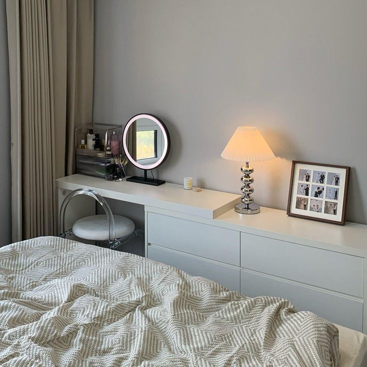 a white bed sitting next to a dresser with a mirror on top of it