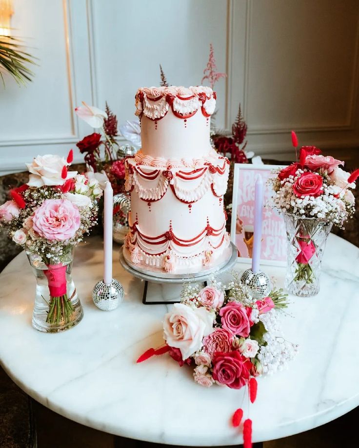 a three tiered cake sitting on top of a table next to flowers and candles