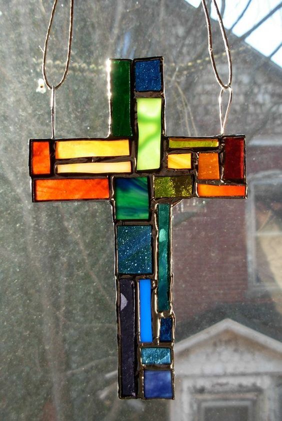 a stained glass cross hanging from a window