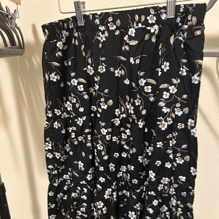 Black Skirt With White Floral Detail. Never Worn. Black Floral Print Maxi Skirt For Spring, Black Floral Print Skirt For Vacation, Black Floral Print Flowy Skirt, Black Flowy Floral Skirt, Black Skirted Bottoms With Floral Print, Black Spring Vacation Maxi Skirt, Chic Black Floral Print Maxi Skirt, Black Maxi Skirt For Spring Vacation, Black Floral Print Tiered Maxi Skirt