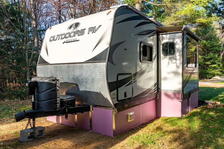 an rv is parked in the grass near some trees