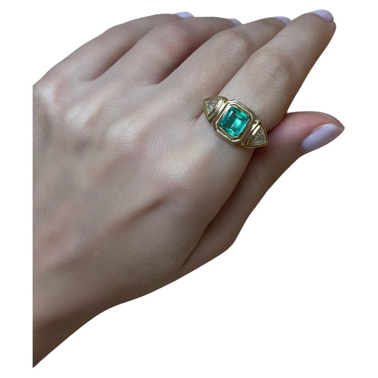 This exquisite 18-karat gold ring is centered with a natural emerald and paired with two natural trillion-cut diamonds, in a geometric stepped setting. The ring weighs just over 6grams of gold, giving it a luxurious feel. It's three stone design is timeless, and the setting of the stones allows the wearer to enjoy it on the daily as the stones are protected due to their bezel style setting. The Emerald is 1.50cts and the diamonds are 0.25cts each (Color G, Clarity VS/SI). This ring has been made in Cyprus, and can be resized to your desired size. If you would like to receive more photos or videos of this ring simply drop us a message and we will gladly forward these to you. We ship complimentary using DHL Express all across the world. Green Diamond Ring With Vvs Clarity For May Birthstone, Fine Jewelry Green Signet Ring With Birthstone, Green Vvs Clarity Birthstone Ring For Anniversary, Green Diamond Ring With Vvs Clarity In 14k Gold, 14k Gold Green Emerald Ring With Center Stone, Green Emerald Signet Ring With Birthstone Detail, Heirloom Style Green Emerald Ring With Center Stone, Heirloom Green Emerald Ring With Center Stone, Green Diamond Signet Ring In Fine Jewelry Style