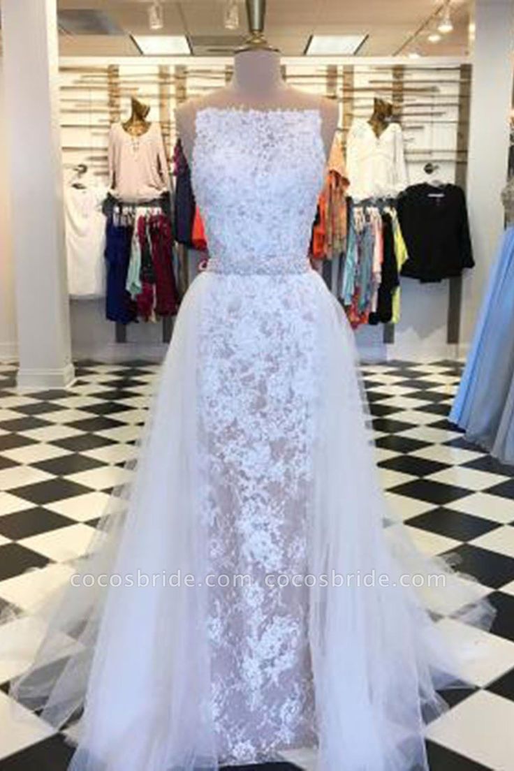 a white wedding dress on display in a clothing store with mannequins and dresses