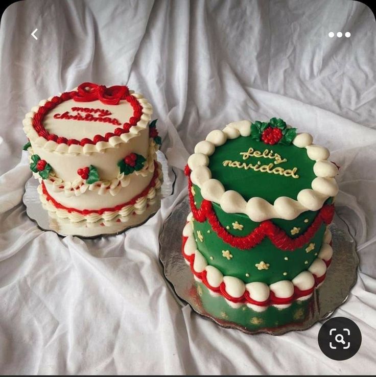 two decorated cakes sitting on top of a white tablecloth covered table next to each other