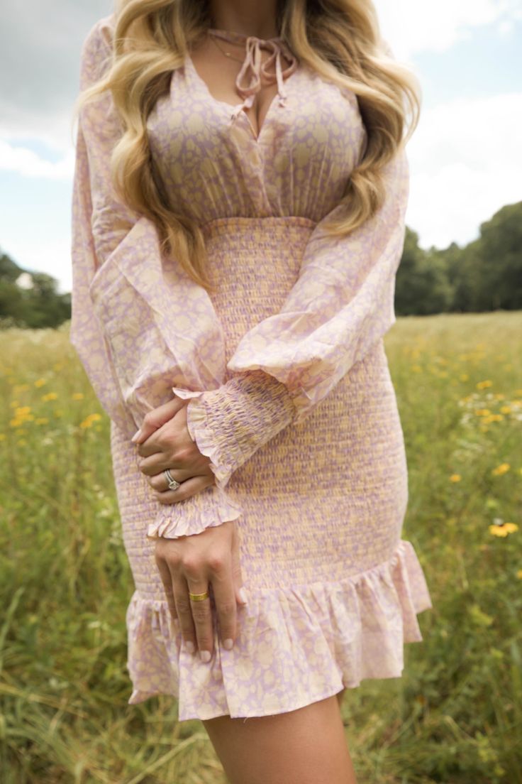 This is a lavender smocked dress featuring bubble sleeves and a ruffled hem. The model is wearing a size small. Spring Cute Puff Sleeve Dress With Smocked Bodice, Cute Puff Sleeve Dress With Smocked Bodice For Spring, Cute Fitted Puff Sleeve Dress With Smocked Bodice, Summer Pink Smocked Dress With Ruffled Sleeves, Feminine Pink Puff Sleeve Dress With Smocked Bodice, Cute Fitted Smocked Dress With Ruffle Hem, Pink Puff Sleeve Dress With Smocked Bodice For Brunch, Pink Smocked Puff Sleeve Dress, Purple Fitted Dress With Smocked Bodice