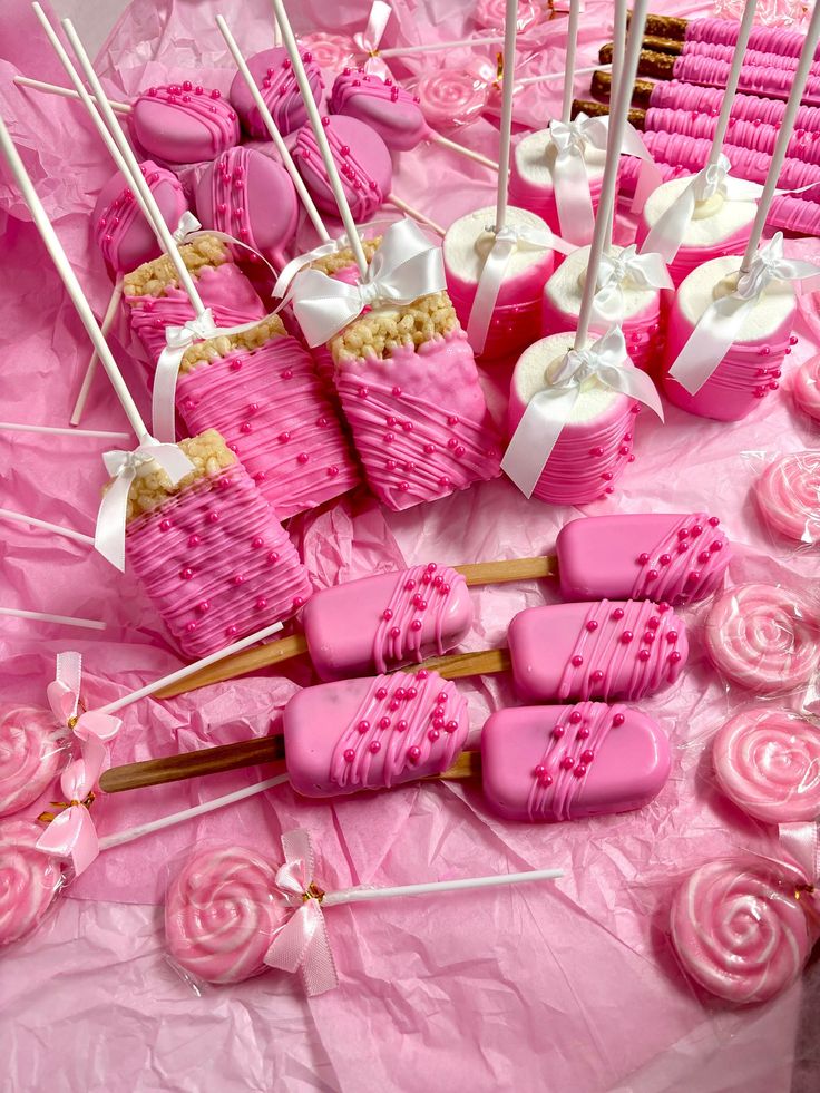 pink candy lollipops and marshmallow candies are arranged on a table