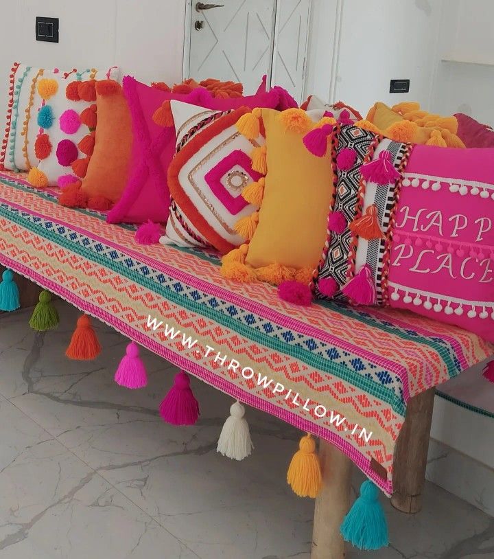 a bench with colorful pillows and tassels on it