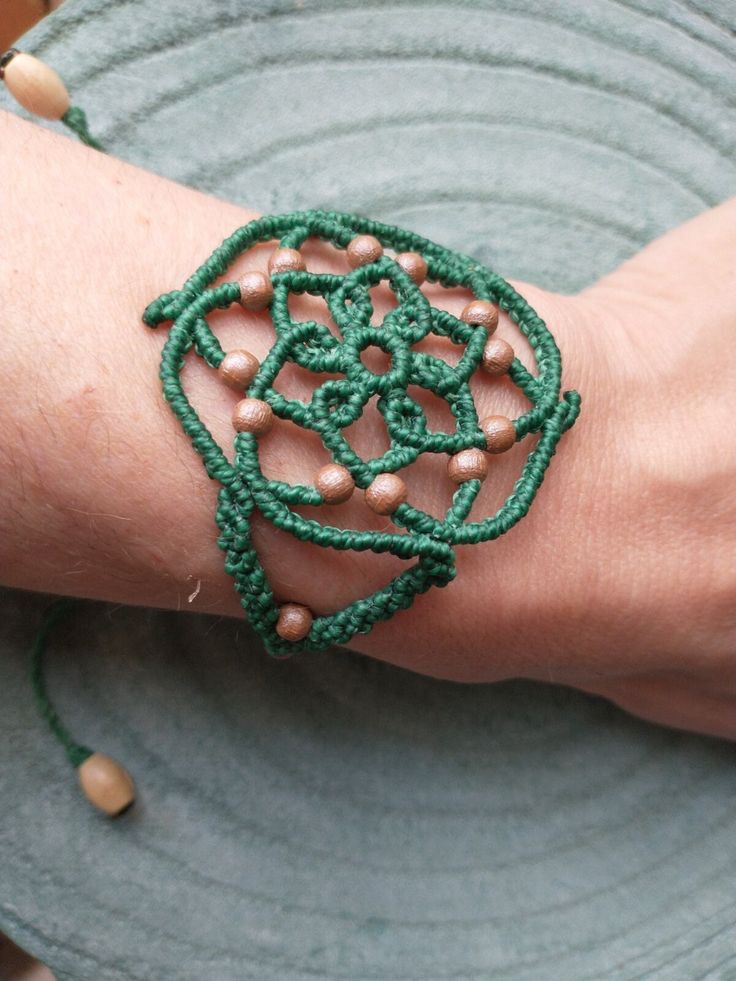 I have made this bracelet in grass green combined with a toasted beige color present in the wooden beads that adorn the bracelet. It is a bracelet with a mandala design and boho style, very light and attractive. The closure is sliding, so the bracelet can be adjusted to the desired size. I have finished it with two raw-colored wooden beads that hang from the ends of the chain. The width of the widest part of the bracelet is 5 cm (1.96 in) approx. The maximum length of the chain is approximately Green Bohemian Bracelets With Adjustable Cord, Green Adjustable Cord Bracelets For Festival, Green Adjustable Cord Bracelet For Festival, Green Macrame Friendship Bracelets, Green Macrame Friendship Bracelets For Festivals, Adjustable Green Macrame Bracelets, Green Macrame Beaded Bracelets For Festivals, Green Macrame Braided Bracelets For Festival, Green Macrame Braided Bracelet For Festival