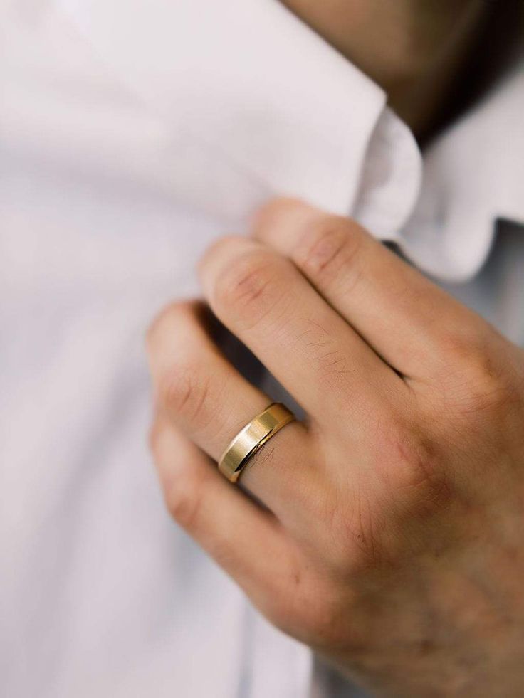 a man wearing a gold wedding band with his hand on the other side of his ring