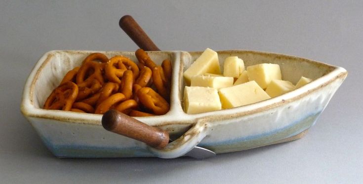 a bowl filled with cheese and pretzels on top of a table next to a knife