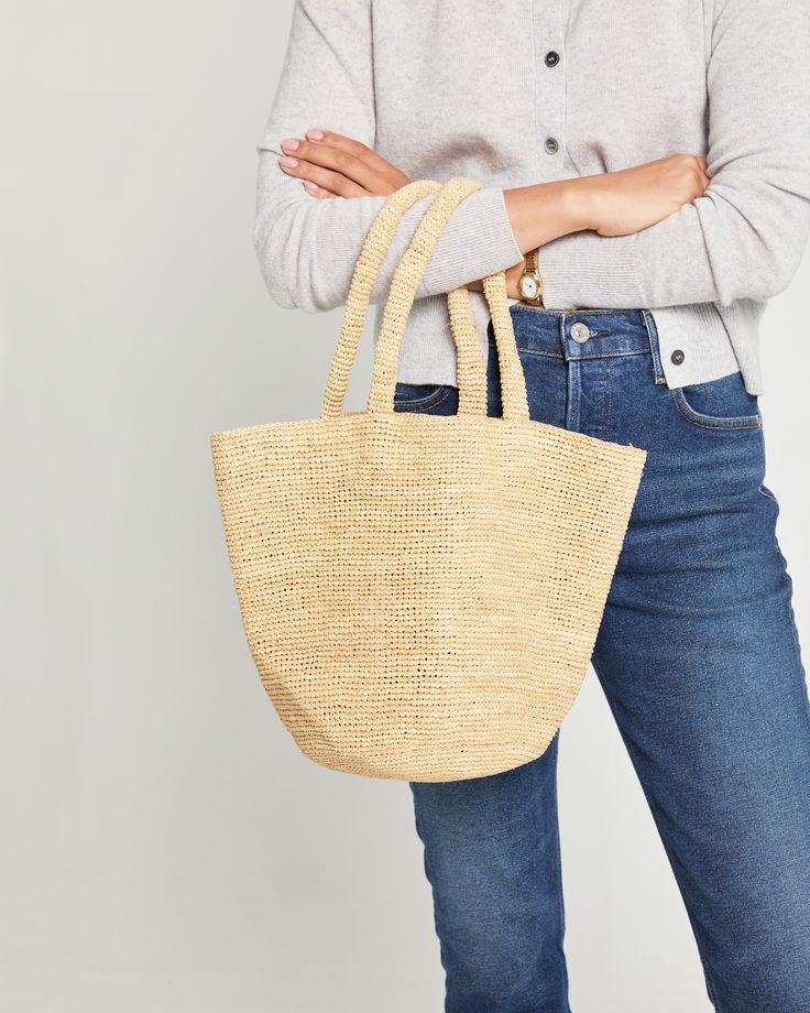 a woman is holding a straw bag in her hands