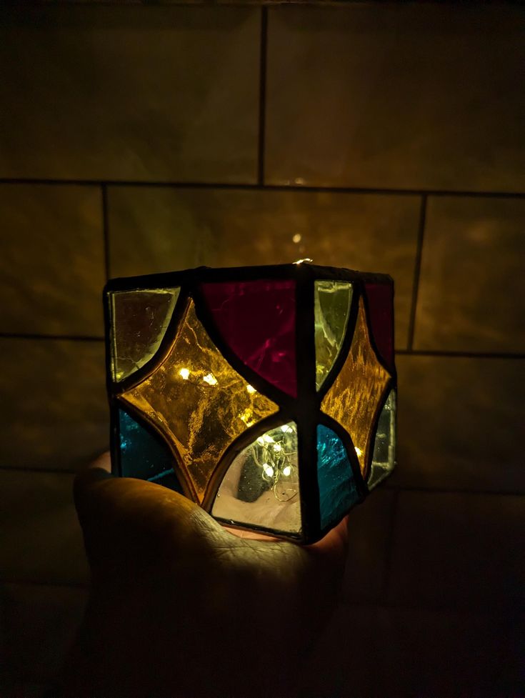 a hand holding up a stained glass lamp