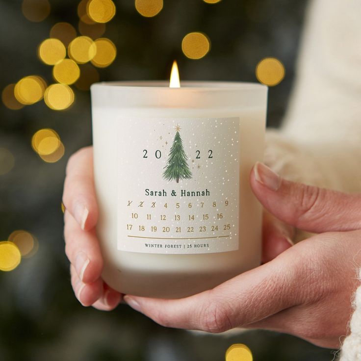 a person holding a candle in front of a christmas tree