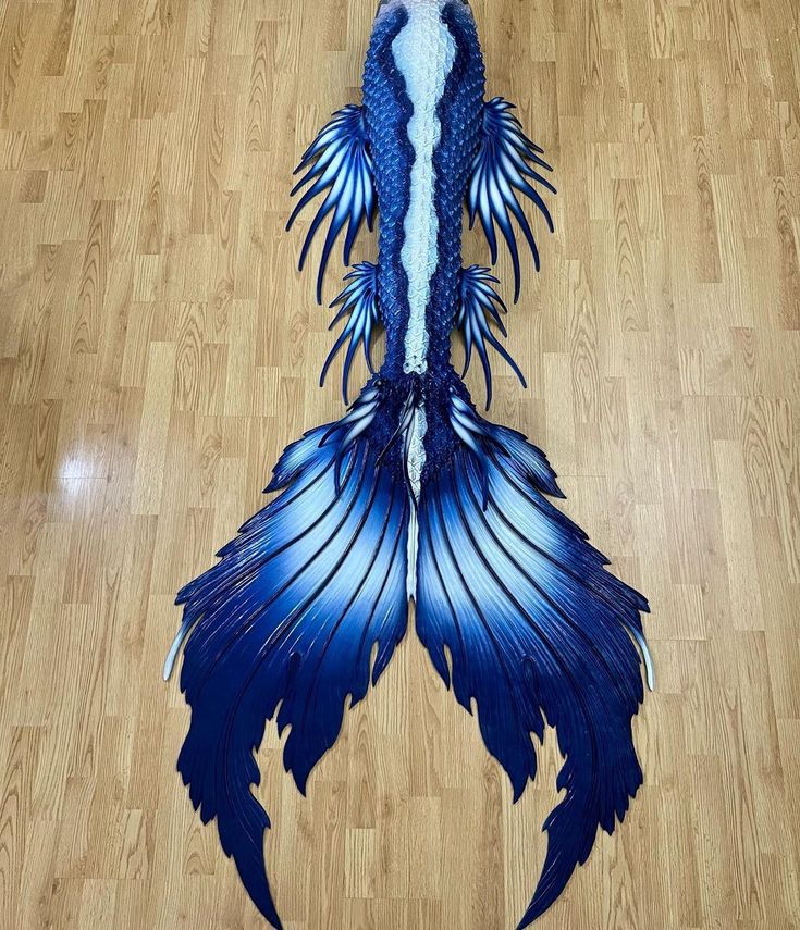 a blue and white dragon tail laying on top of a wooden floor