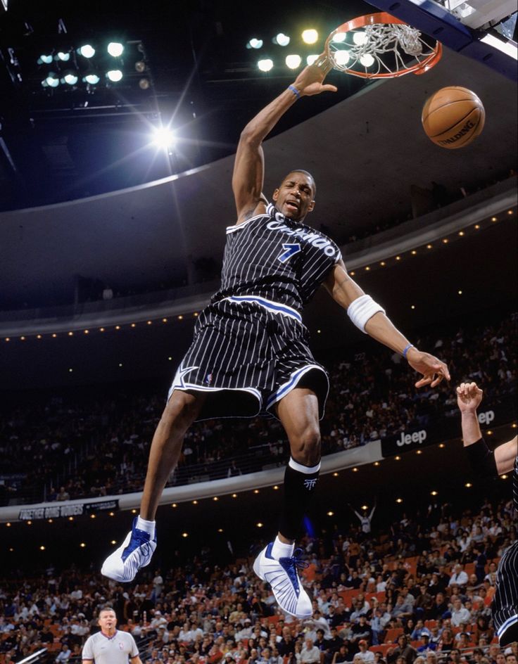 a basketball player dunking the ball in front of an audience at a sporting event