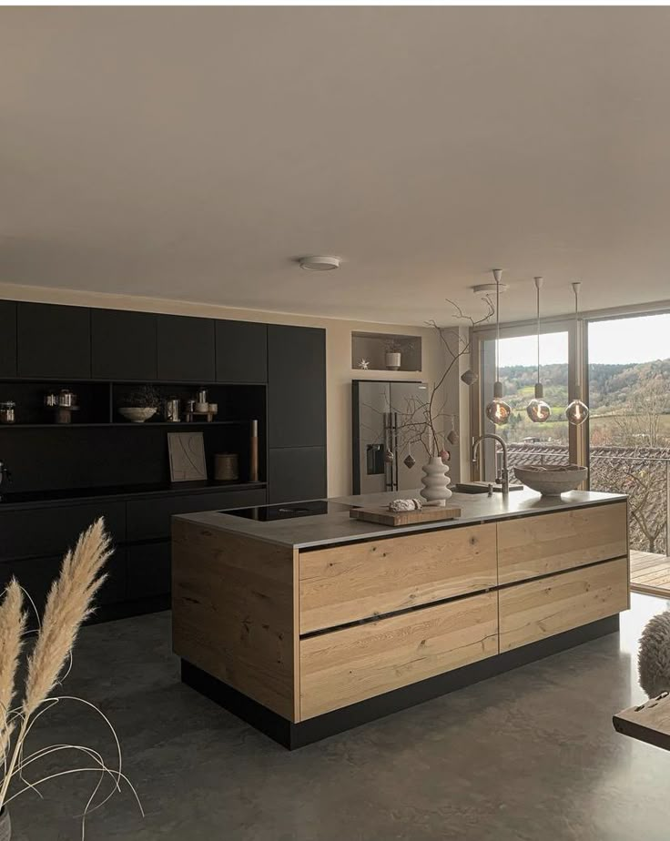 a kitchen with black cabinets and an island countertop in front of a large window