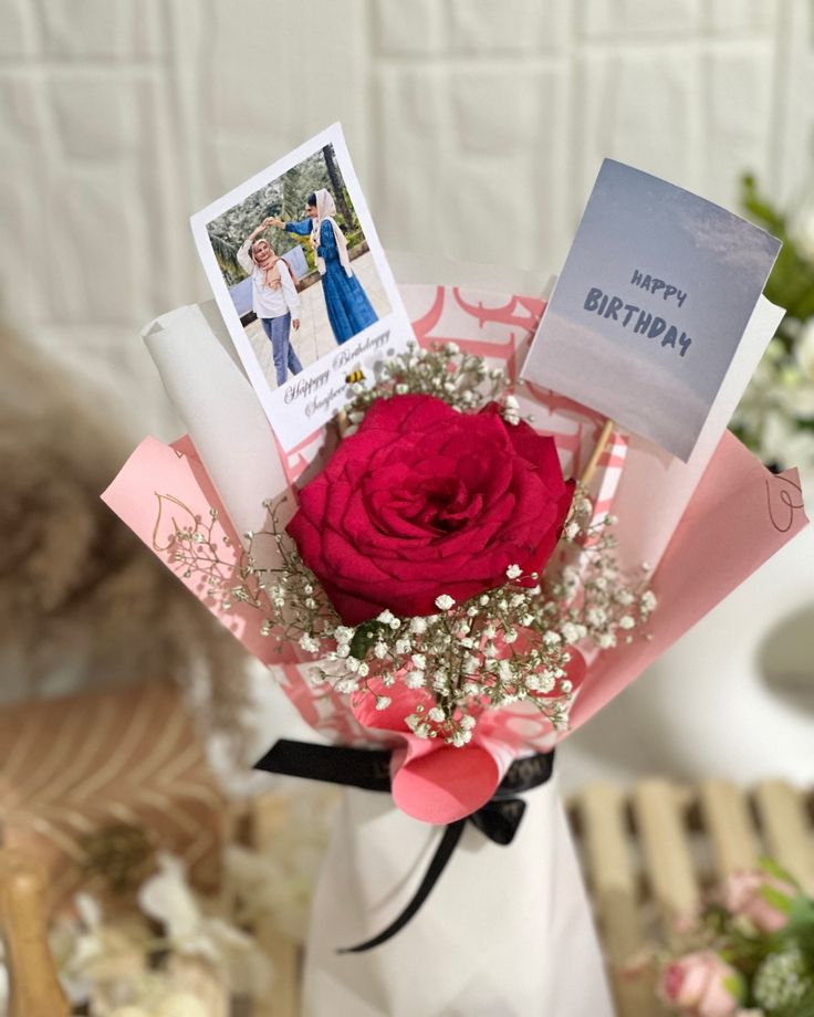 a red rose in a vase with cards and flowers